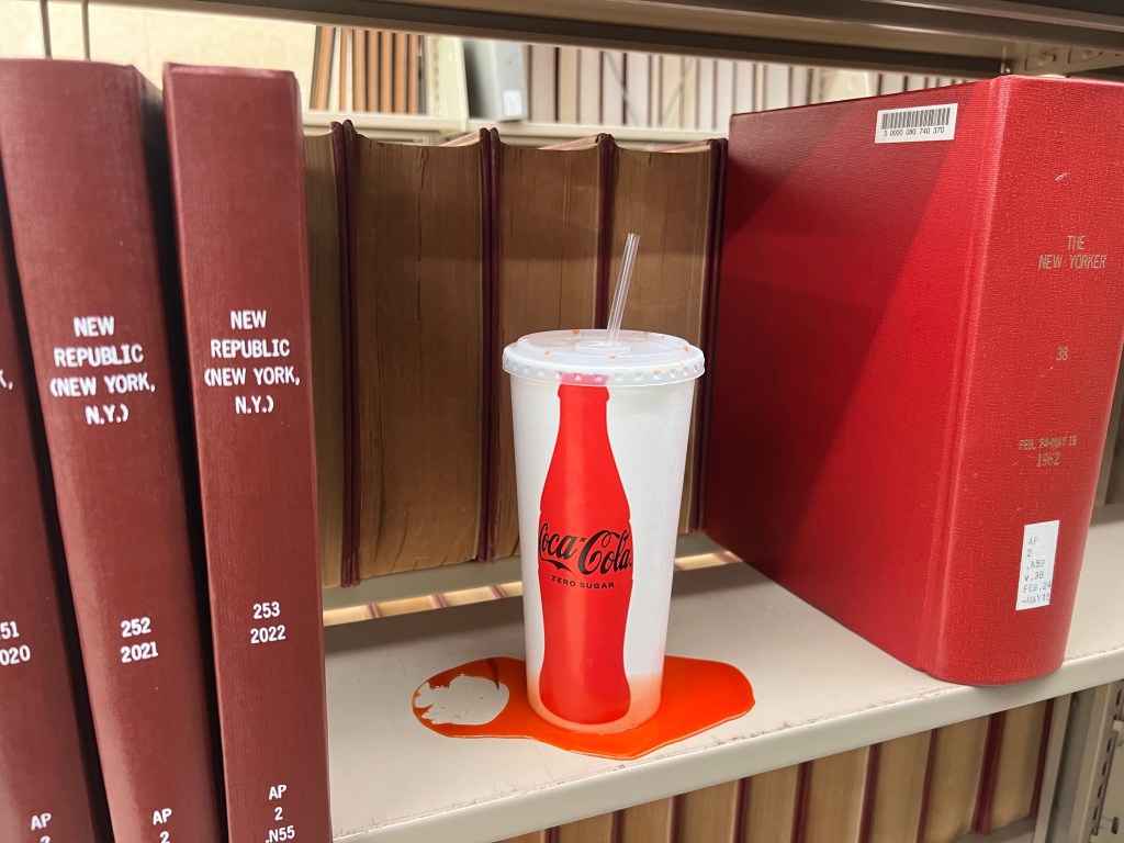 Leaking beverage cup sitting on a library bookshelf